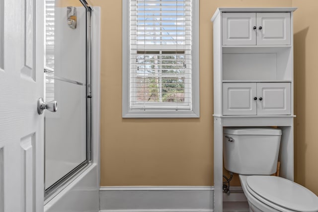 bathroom featuring enclosed tub / shower combo and toilet