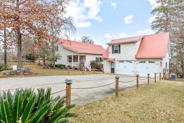 view of front of property with a garage, a porch, a front yard, and central AC unit