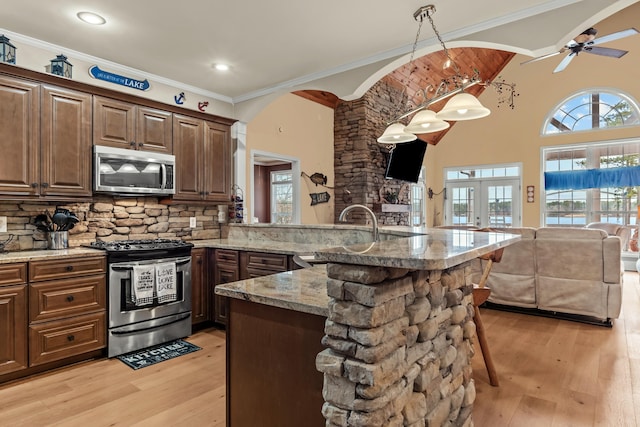 kitchen with a breakfast bar, pendant lighting, sink, kitchen peninsula, and stainless steel appliances