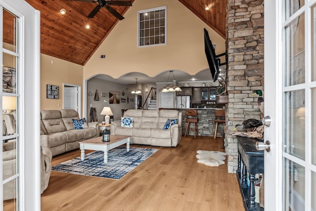 living room with high vaulted ceiling, ceiling fan with notable chandelier, wooden ceiling, and light wood-type flooring