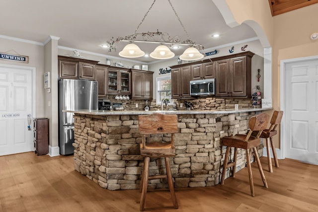 163 Knight Dr, Milledgeville, GA 31061 - kitchen featuring appliances with stainless steel finishes, dark brown cabinetry, a kitchen breakfast bar, backsplash, and crown molding