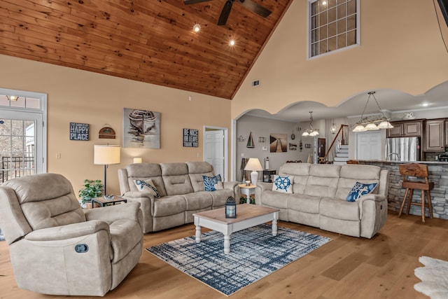 living room featuring wood ceiling, ceiling fan with notable chandelier, high vaulted ceiling, and light wood-type flooring