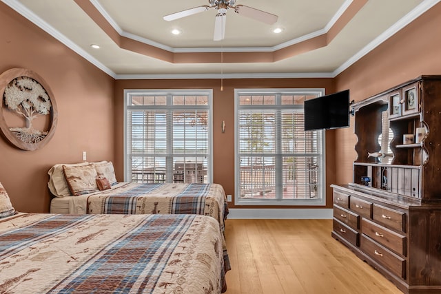 bedroom featuring crown molding, multiple windows, a raised ceiling, and light hardwood / wood-style flooring