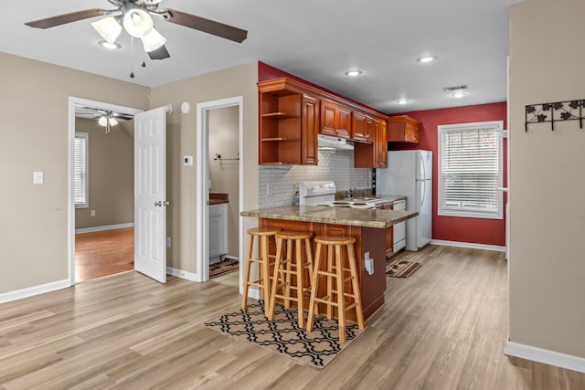 kitchen with white appliances, ceiling fan, backsplash, kitchen peninsula, and light wood-type flooring