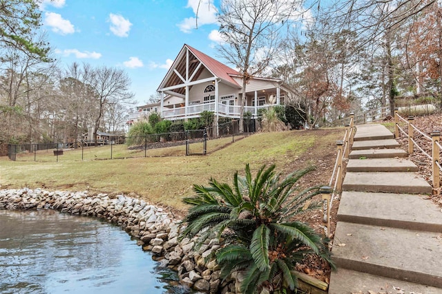 back of property featuring a water view and a yard