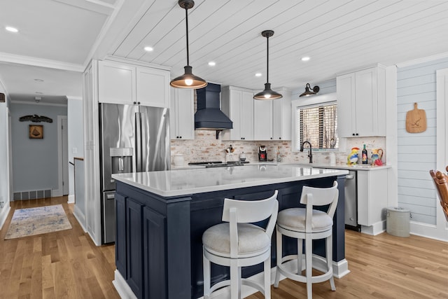 kitchen featuring custom exhaust hood, white cabinetry, a kitchen island, and hanging light fixtures