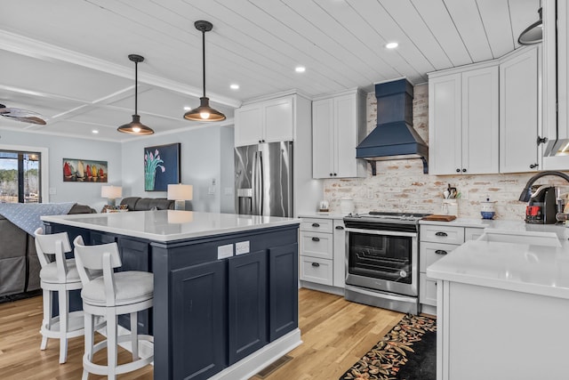 kitchen featuring sink, appliances with stainless steel finishes, custom range hood, pendant lighting, and white cabinets