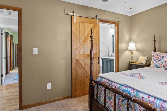 carpeted bedroom featuring connected bathroom and a barn door