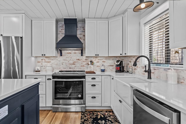 kitchen with stainless steel appliances, white cabinetry, custom range hood, and wood ceiling