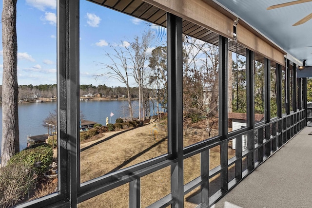 unfurnished sunroom featuring ceiling fan and a water view