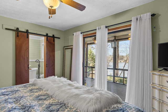 bedroom with a barn door, access to outside, connected bathroom, and a textured ceiling