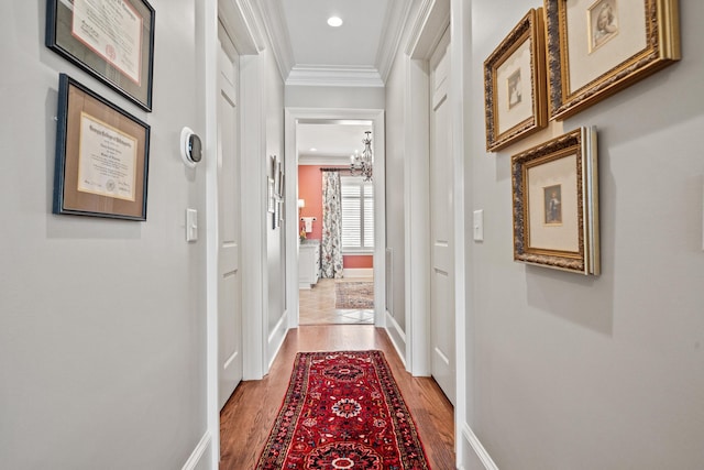 hall with a notable chandelier, crown molding, and hardwood / wood-style flooring