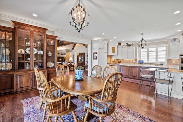 dining area featuring an inviting chandelier, ornamental molding, dark hardwood / wood-style floors, and sink