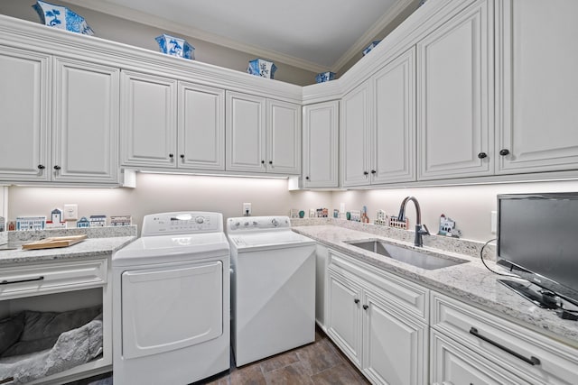 washroom with dark wood-type flooring, sink, cabinets, washer and dryer, and ornamental molding