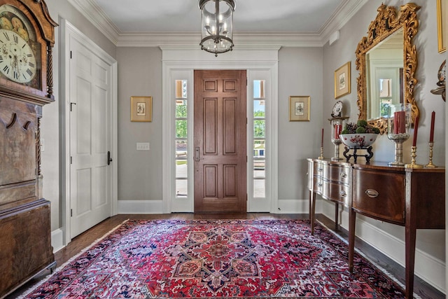 entryway with hardwood / wood-style flooring, crown molding, and an inviting chandelier