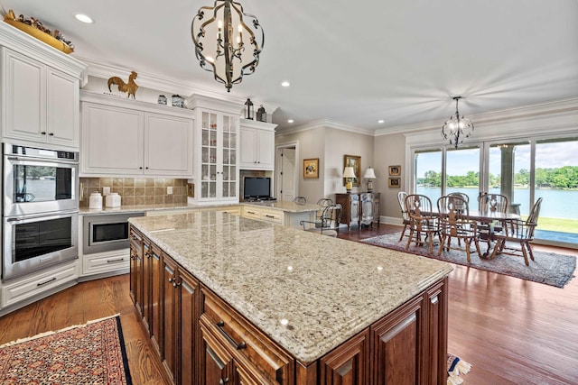 kitchen featuring stainless steel appliances, a kitchen island, white cabinets, and an inviting chandelier