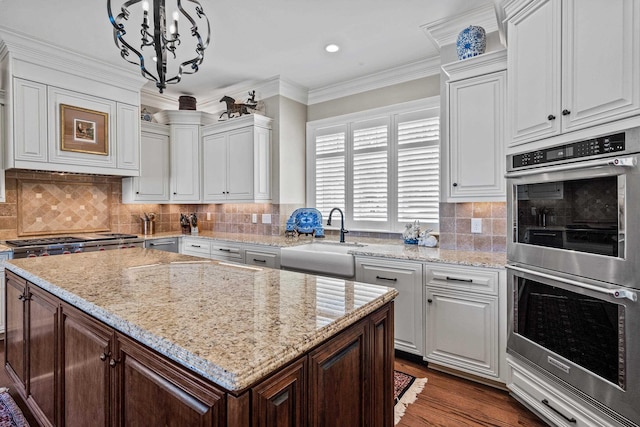 kitchen with sink, white cabinetry, decorative light fixtures, ornamental molding, and appliances with stainless steel finishes