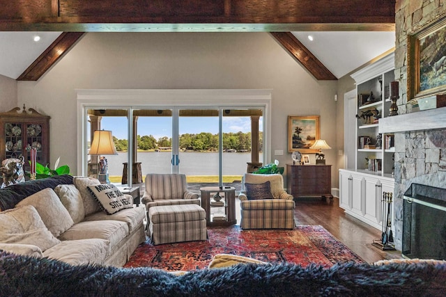 living room with built in shelves, dark wood-type flooring, vaulted ceiling with beams, a water view, and a fireplace