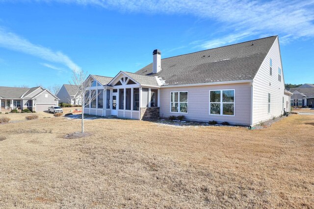 rear view of house with a yard and a sunroom