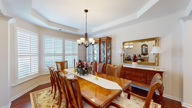 dining area with a tray ceiling, dark hardwood / wood-style floors, and a chandelier