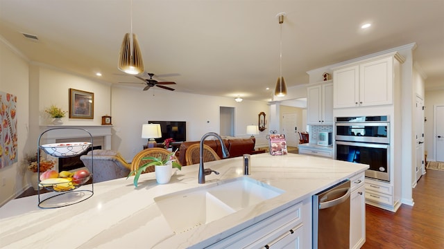 kitchen featuring sink, white cabinetry, stainless steel appliances, light stone countertops, and decorative light fixtures