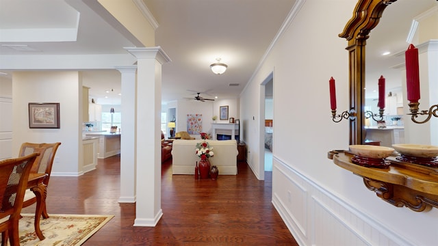 hall featuring decorative columns, crown molding, and dark hardwood / wood-style floors