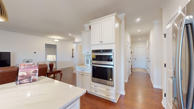 kitchen with crown molding, white cabinetry, stainless steel appliances, dark hardwood / wood-style floors, and light stone counters