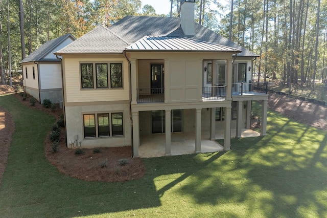 rear view of house featuring a balcony, a patio area, and a lawn