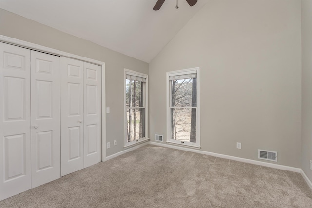 unfurnished bedroom with visible vents, baseboards, carpet, and high vaulted ceiling