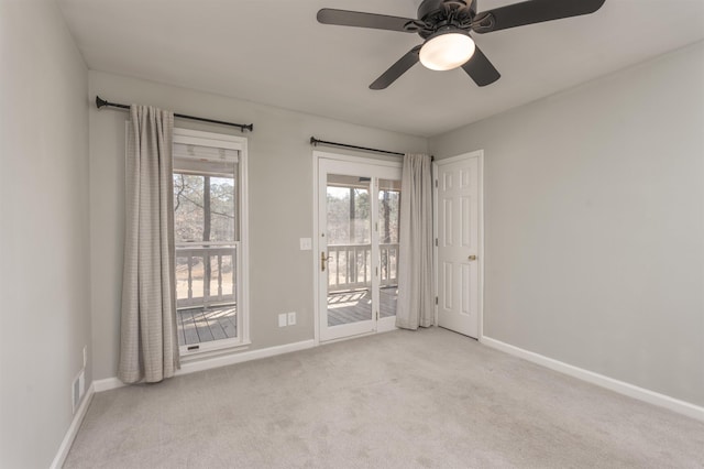 spare room featuring light carpet, a ceiling fan, and baseboards