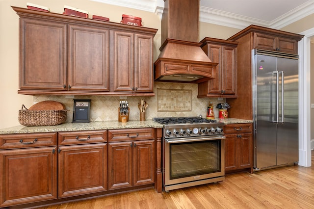 1051 Swift Crk, Greensboro, GA 30642 - kitchen with high quality appliances, custom exhaust hood, light wood-style flooring, light stone counters, and ornamental molding
