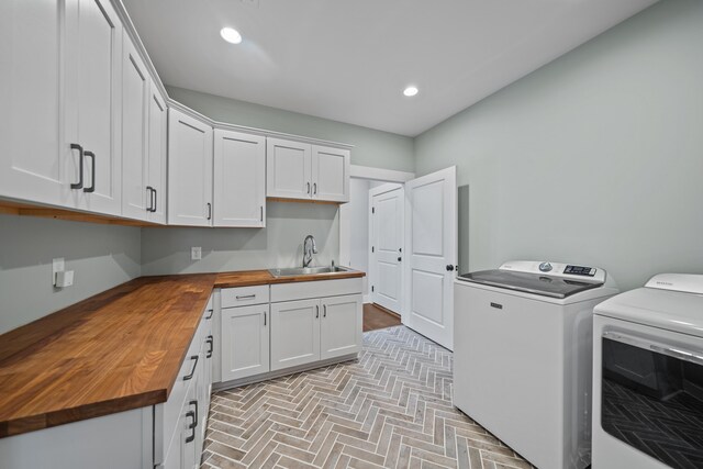 washroom featuring cabinet space, brick floor, washing machine and dryer, a sink, and recessed lighting