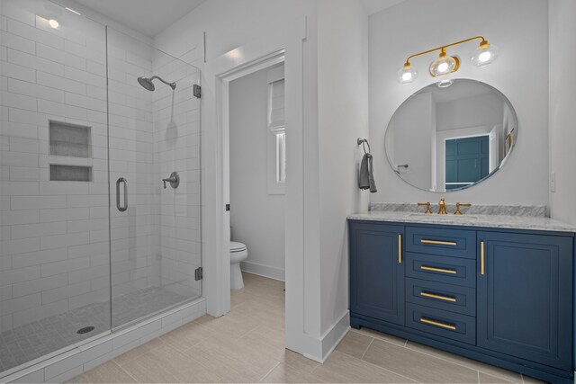 bathroom featuring a stall shower, vanity, toilet, and baseboards