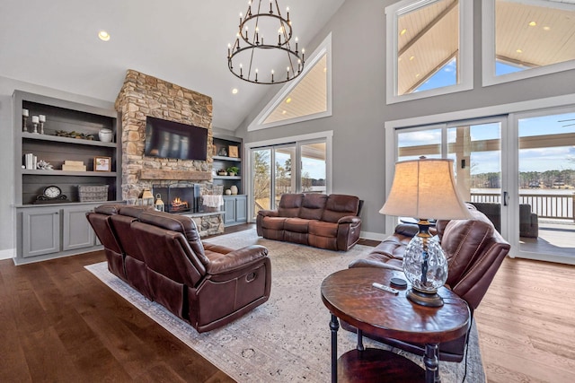 living area with baseboards, built in features, wood finished floors, and a stone fireplace