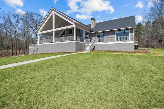 view of front of property with a front yard, a chimney, stairway, and a wooden deck