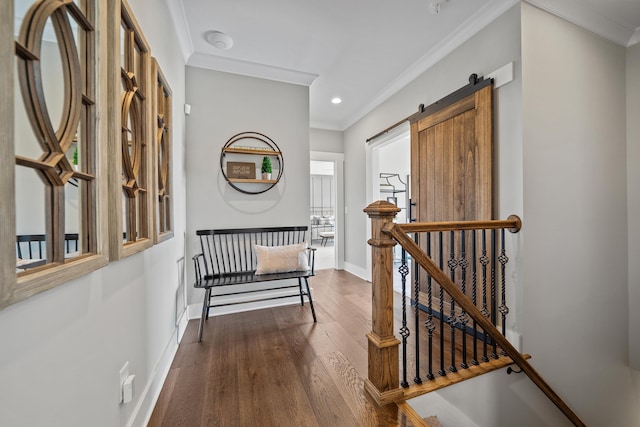 hall featuring a barn door, dark wood-type flooring, an upstairs landing, baseboards, and crown molding