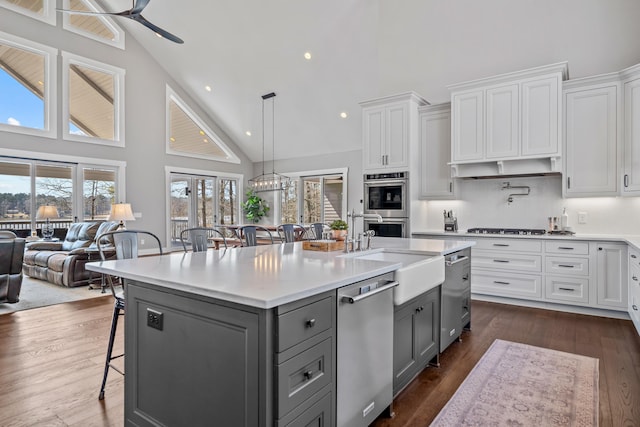 kitchen with stainless steel appliances, gray cabinetry, white cabinets, a sink, and a kitchen breakfast bar