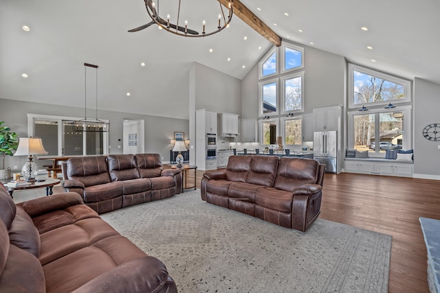 living room with hardwood / wood-style flooring, plenty of natural light, high vaulted ceiling, and an inviting chandelier