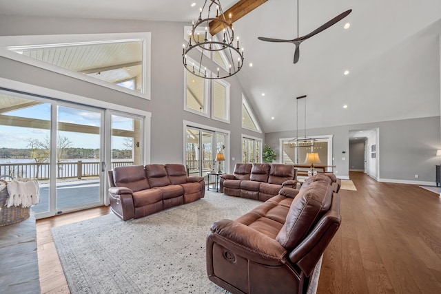 living area featuring french doors, a water view, an inviting chandelier, wood finished floors, and baseboards