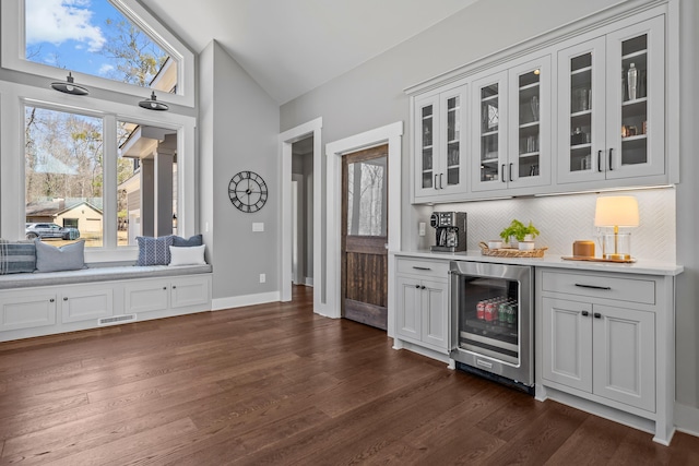 bar featuring lofted ceiling, beverage cooler, decorative backsplash, and dark wood-type flooring