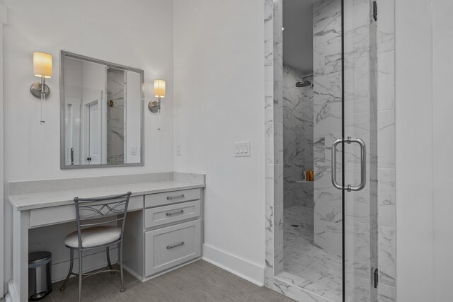 full bathroom featuring a marble finish shower, vanity, and baseboards