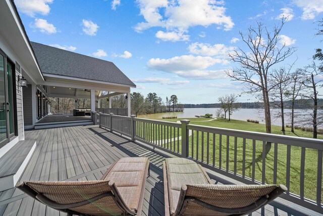 wooden terrace with a water view and a yard