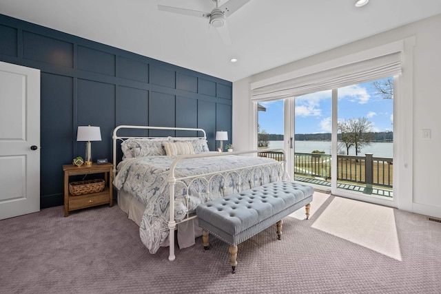 bedroom featuring a water view, access to outside, a decorative wall, and carpet flooring