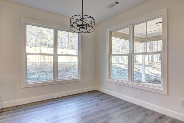 unfurnished dining area featuring an inviting chandelier and hardwood / wood-style floors