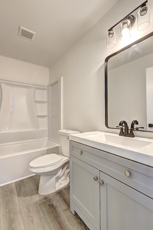 full bathroom with vanity, hardwood / wood-style floors, shower / bathtub combination, and toilet