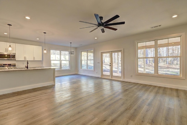 unfurnished living room with hardwood / wood-style floors, sink, french doors, and ceiling fan