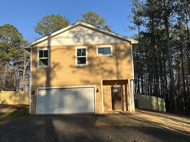 view of front facade with a garage, driveway, and fence