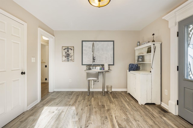 foyer entrance featuring baseboards, a healthy amount of sunlight, and light wood-style floors