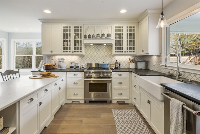 kitchen with white cabinets, dark wood-style flooring, hanging light fixtures, stainless steel appliances, and a sink