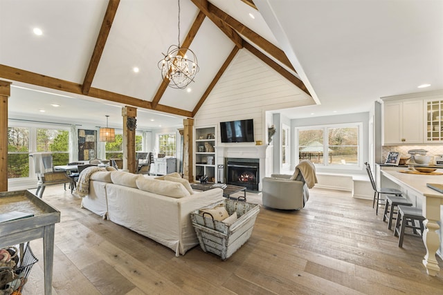 living room featuring light wood-style floors, plenty of natural light, and a lit fireplace